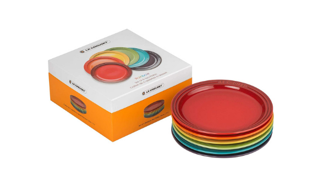 a stack of colourful plates next to a le creuset box