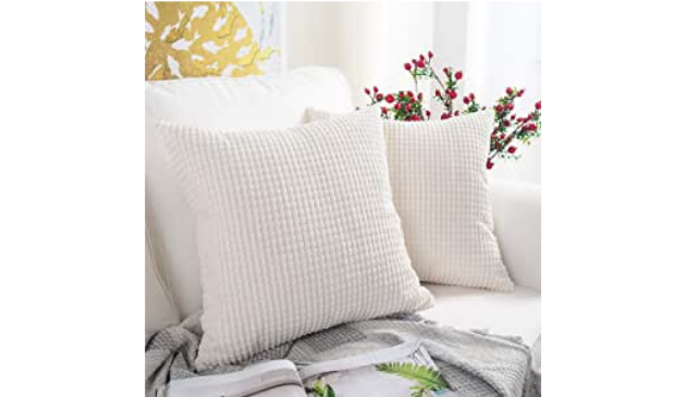 Two textured white cushions on a white sofa
