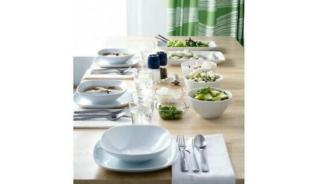 a table laid with square white crockery