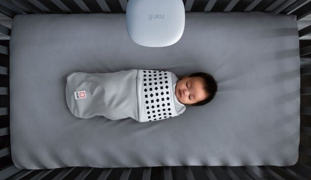 baby wearing Nanit sleepsuit in cot