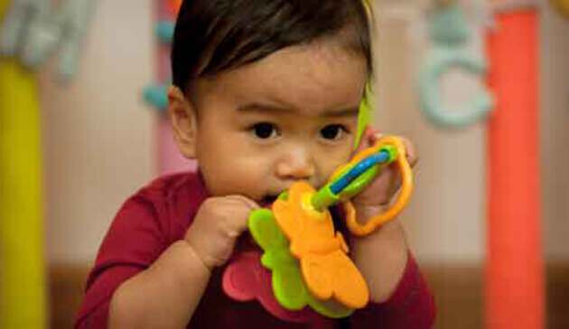 Nine month old baby holding toy