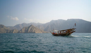 A boat ontop of the water with rugged mountains in the background