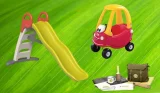 A green, red and grey plastic children's slide sits next to a red and yellow Cozy Coupe ride-on car, with a dark green Den Kit below. The background is a mix of mid and light green and looks like grass