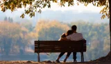 A couple sit on a bench looking into the distance