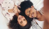 A mother and child take a selfie on the bed from above