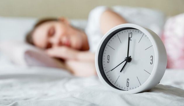 alarm clock with woman sleeping in background