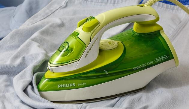 A picture of a green and white Philips EcoCare steam iron on some light coloured denim.