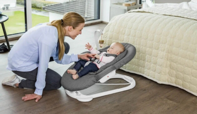 Mother playing with baby laying in Stokke Steps Bouncer
