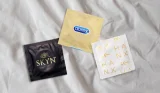 A picture of three condoms from Skyn, Durex and HANX on top of a bedsheet
