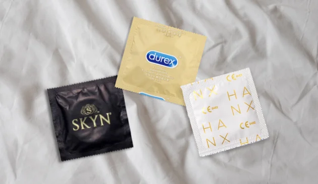 A picture of three condoms from Skyn, Durex and HANX on top of a bedsheet