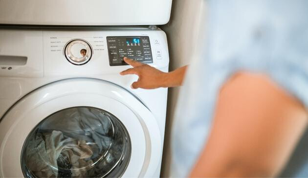 A picture of a person setting the programmes on a washing machine.