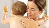 Mother rubbing lotion on baby's back