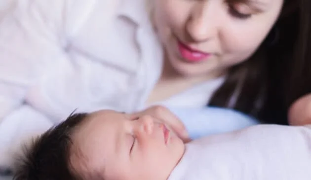 Woman looking down at a sleeping baby